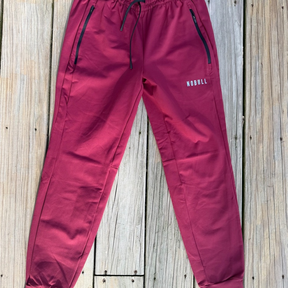 New NOBULL Joggers Men’s Medium Burgundy Zip Pockets Stretch Athletic Pants $89